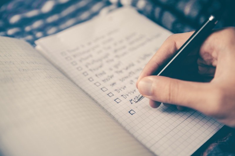 hand filling checklist on notebook 
