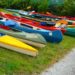 Different types of canoes an kayaks laying on the grass