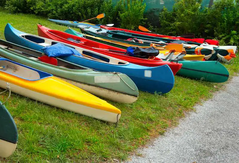 Different types of canoes an kayaks laying on the grass