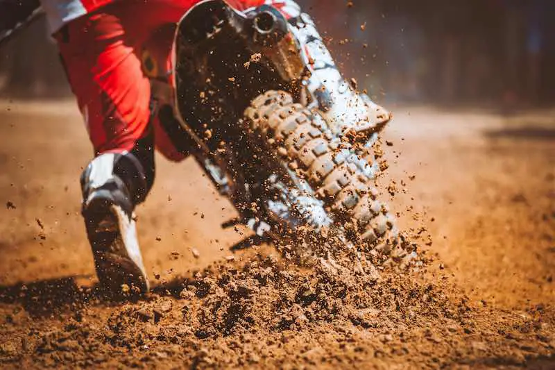 Man in red suit riding a dirt bike on a motocross grouns