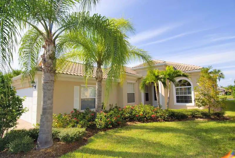 Beautiful Florida home with green grass and palm trees on a sunny day