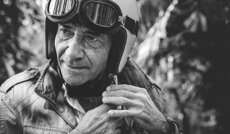 Black and white photo of an old biker wearing a retro vintage motorcycle helmet