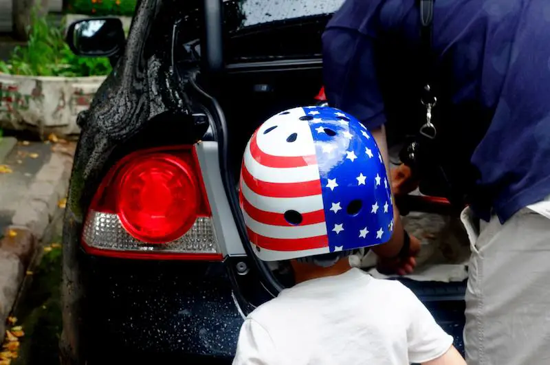 A boy wearing a bicycle helmet painted the USA flag colors