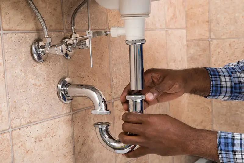 Man checking for leaks under a sink