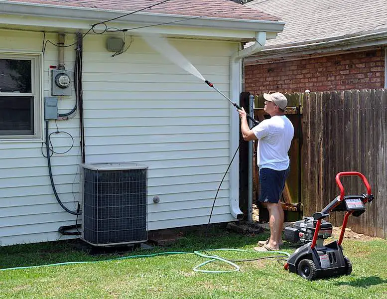 Man cleaning house exterior walls using a pressure washer