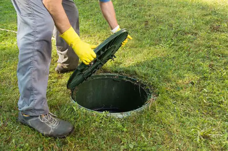 man opening the hatch of a septic tank