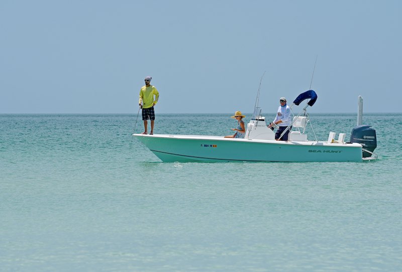 People fishing in open water from a white boat