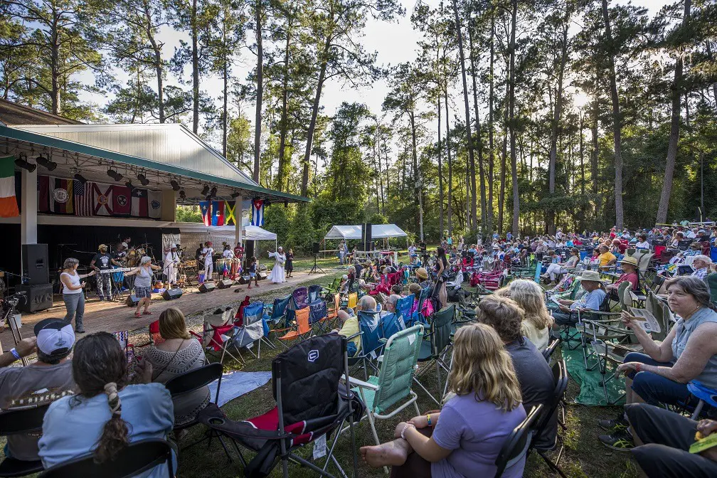 Group of people sitting outside in lawn chairs facing a state of musical performers