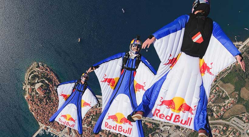 3 Redbull Skydive team performers flying through the air in their wingsuits. 