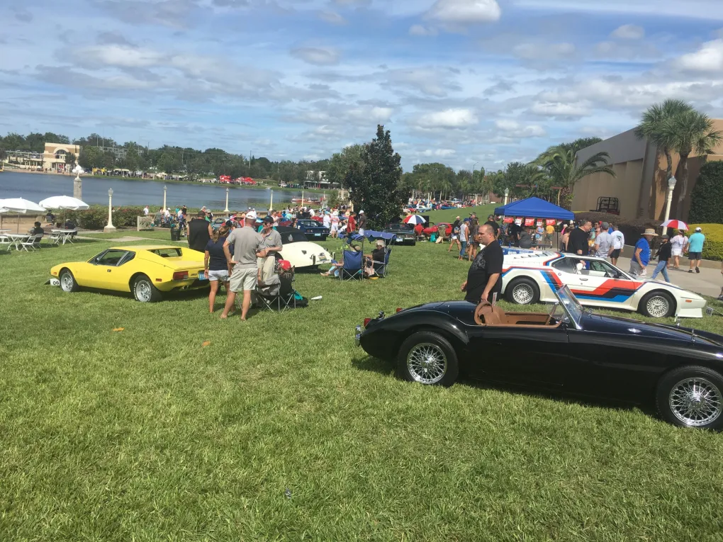 Lake Mirror Car Show. Cars are parked in the grass beside the lake with people walking around looking at the cars