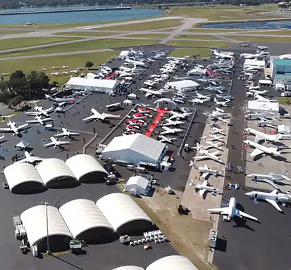 Aerial view of Orlando Executive Airport - hangars and lots of large and small airplanes lined up in rows.