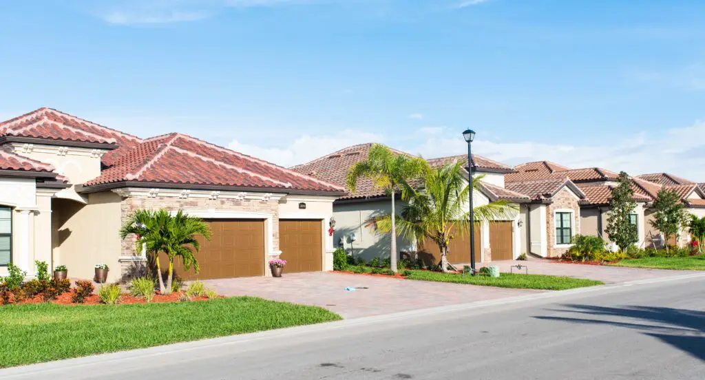 2 bungalow homes built in a Florida golf community. A few palm trees dot each property.