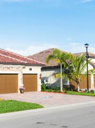 2 bungalow homes built in a Florida golf community. A few palm trees dot each property.