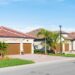 2 bungalow homes built in a Florida golf community. A few palm trees dot each property.