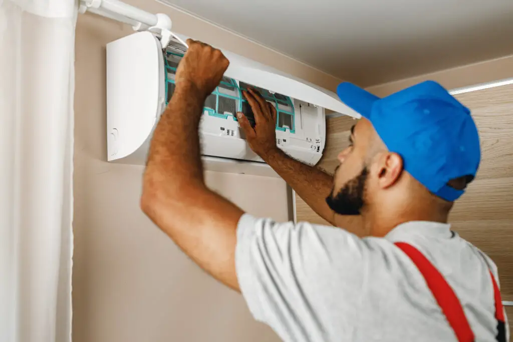 Man in blue ball cap repairing a mini-split air conditioner